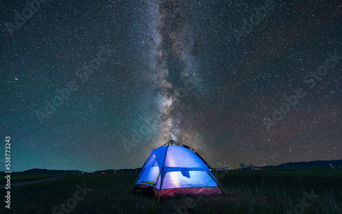 the blue tent is on the grassland. The tent is under the stars