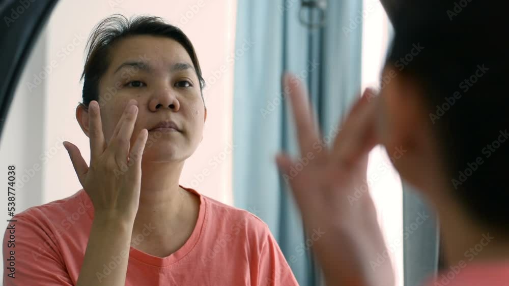 close up asian woman face applying face cream to take care of the face After bathing in a room with daylight close up asian woman face applying face cream to take care of the face After bathing in a room with daylight