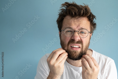 Man woke up after a party, he touches his beard and is puzzled by his untidy appearance. Copy space. Alcohol addiction concept.