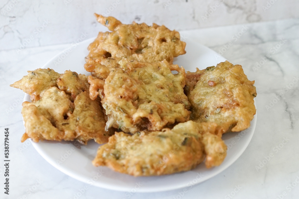 Bakwan goreng, fried food, Indonesian traditional street food snacks. fried vegetables dough fritters, appetizer on a white plate Bakwan goreng, fried food, Indonesian traditional street food snacks. fried vegetables dough fritters, appetizer on a white plate