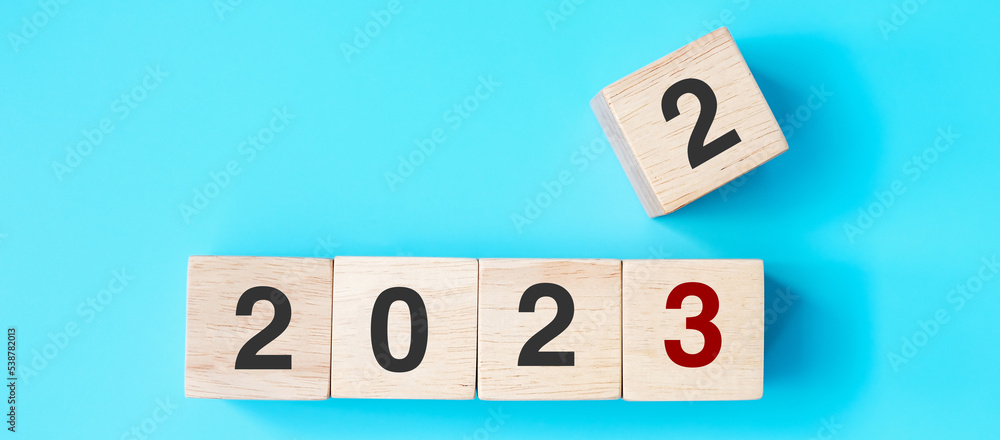 hand holding wooden cube block with 2023 text on blue background. Resolution, plan, review, goal, start and New Year holiday concepts hand holding wooden cube block with 2023 text on blue background. Resolution, plan, review, goal, start and New Year holiday concepts