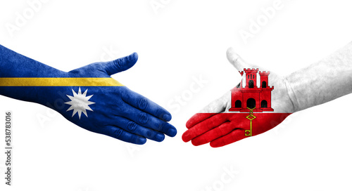 Handshake between Gibraltar and Nauru flags painted on hands, isolated transparent image. photo