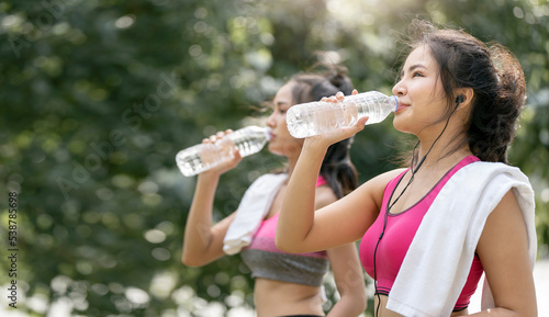 Two Beautiful asian sportswoman drinking water after workout or exercise outdoors, copy space.