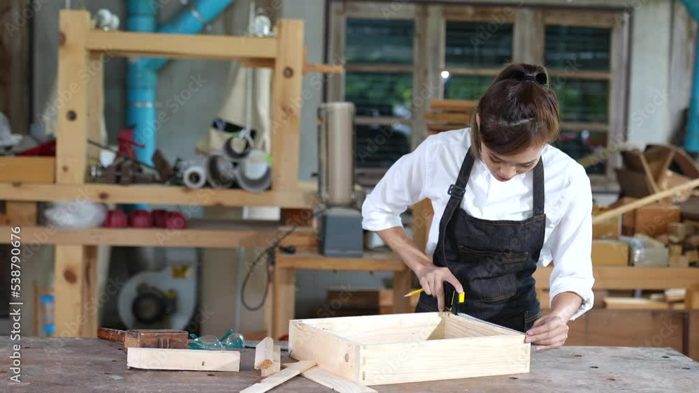 portrait of beautiful asian woman carpenter dealing with handicraft, woman has own business connected with making wooden furniture in workshop ,cinema tone portrait of beautiful asian woman carpenter dealing with handicraft, woman has own business connected with making wooden furniture in workshop ,cinema tone