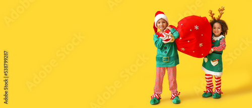 Cute little elves holding Santa bag on yellow background with space for text
