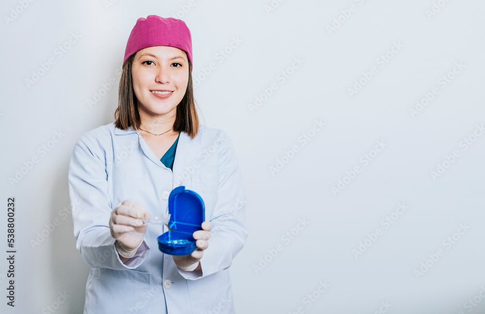 A dentist with retainers on isolated background, Portrait of smiling dentist with dental retainers isolated. Smiling young dentist showing some retainers A dentist with retainers on isolated background, Portrait of smiling dentist with dental retainers isolated. Smiling young dentist showing some retainers
