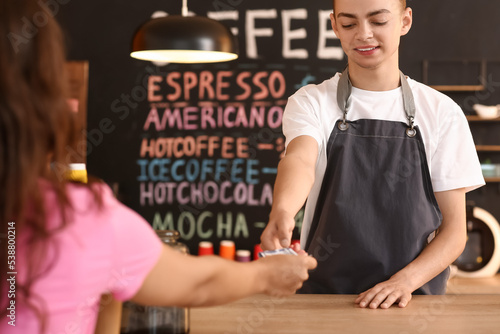 Young male barista receivin...