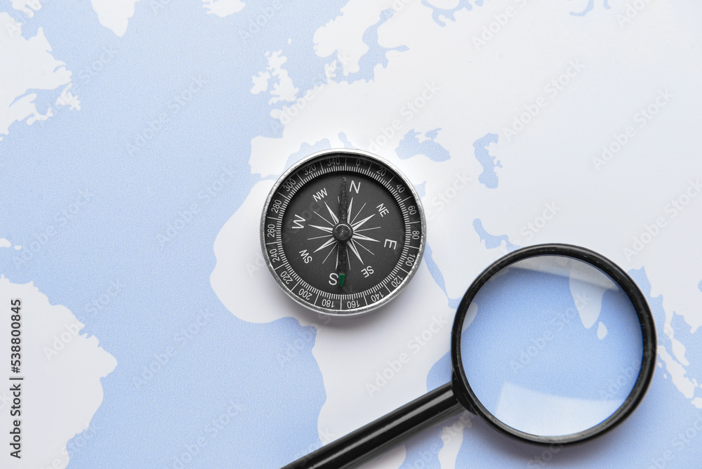 Magnifier and vintage compass on world map