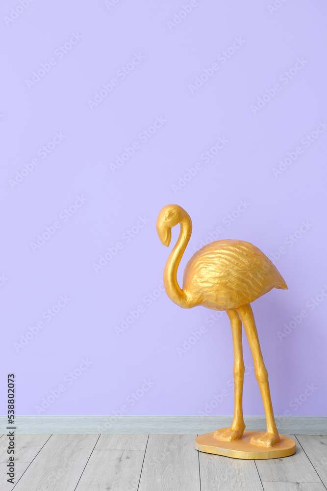 Golden flamingo near violet wall in room Golden flamingo near violet wall in room