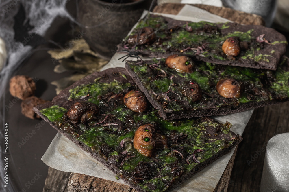 Halloween concept food. Flatbread or pizza with squid Ink, green cheese, mushrooms and purple onion