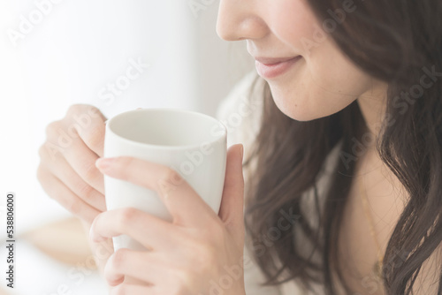 朝、温かい飲み物を飲む女性 