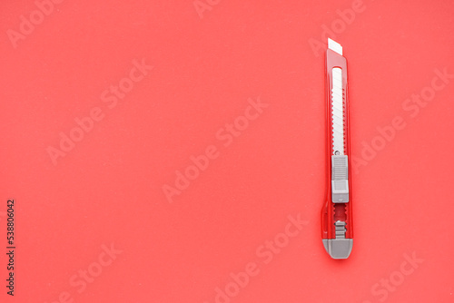 Utility knife on red background © Pixel-Shot