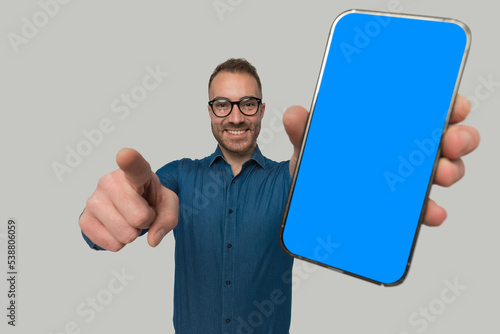 young casual man is pointing finger, showing the telephone photo