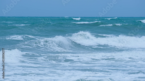 View of sea waves on the beach of tropical seas in Thailand. Strong sea waves crash to shore in the rainy season. Beautiful sea waves with foam of blue and turquoise color.