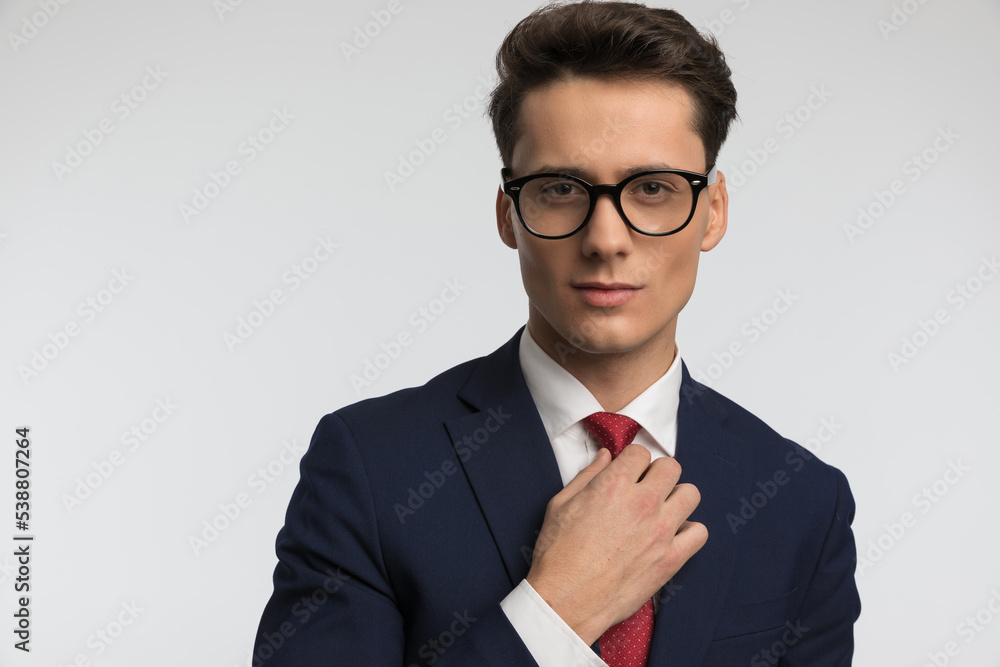 sexy young businessman with glasses in navy blue suit adjusting red tie sexy young businessman with glasses in navy blue suit adjusting red tie