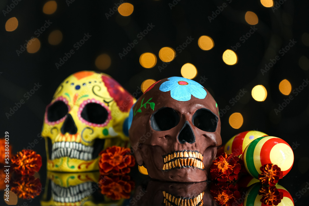 Painted skulls for Mexico's Day of the Dead (El Dia de Muertos), flowers and maracas on dark background Painted skulls for Mexico's Day of the Dead (El Dia de Muertos), flowers and maracas on dark background