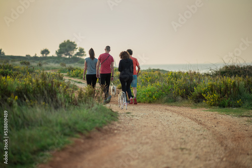 Group of walkers or hikers on a gravel path at a seaside, taking a walk in the evening. Group of people on an evening stroll
