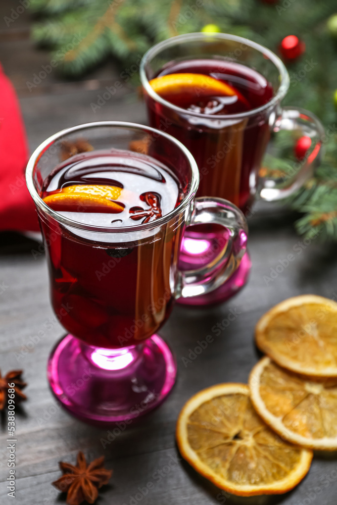 Glasses of tasty mulled wine on dark wooden background, closeup