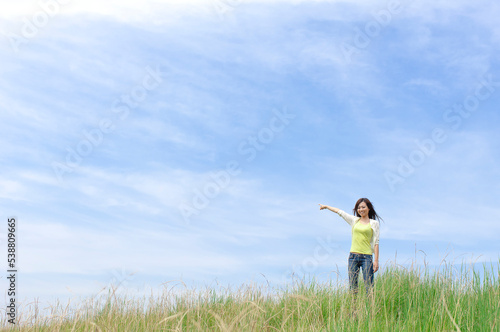 草原で遠くを指差す女性