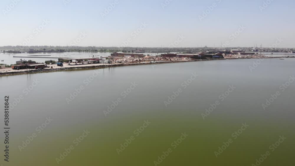 Drone captures an aerial shot of a large lake, a highway, and a large number of tents for flood victims in Pakistan that are set up nearby. Drone captures an aerial shot of a large lake, a highway, and a large number of tents for flood victims in Pakistan that are set up nearby.