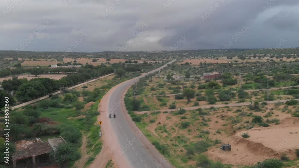 Drone takes an aerial shot of the two biker driving their bike in the isolated highway of the Tharparkar located in the Sindh province of Pakistan Drone takes an aerial shot of the two biker driving their bike in the isolated highway of the Tharparkar located in the Sindh province of Pakistan