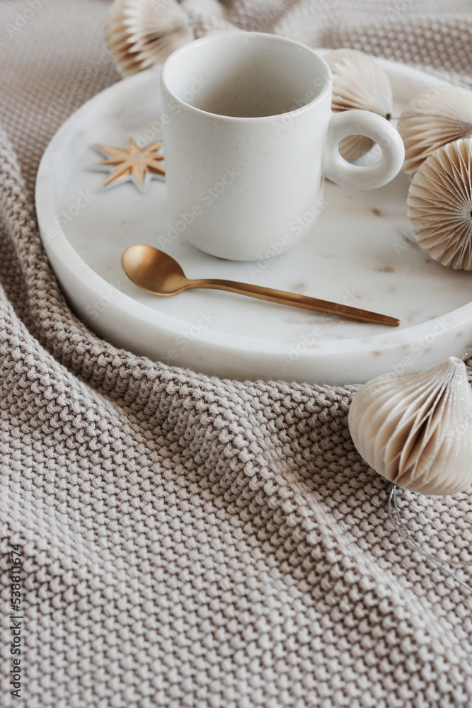 Beige knitting blanket, Christmas tree decorations and cup coffee on marble tray .Xmas scene stationery still life neutral colors.Copy space Beige knitting blanket, Christmas tree decorations and cup coffee on marble tray .Xmas scene stationery still life neutral colors.Copy space