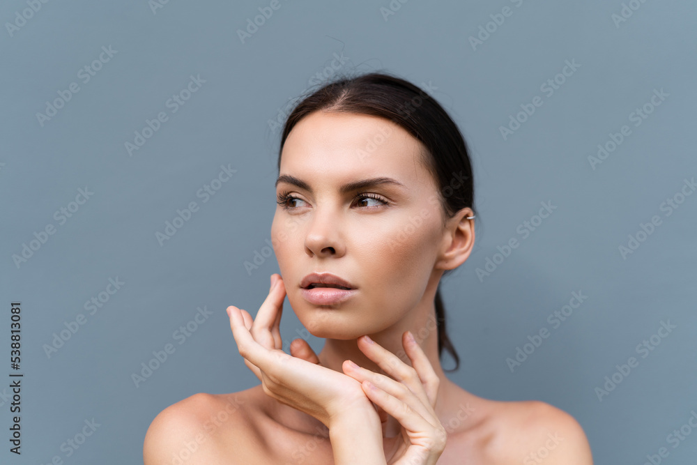 Close-up beauty portrait of a topless woman with perfect skin and natural make-up on light blue wall background Close-up beauty portrait of a topless woman with perfect skin and natural make-up on light blue wall background