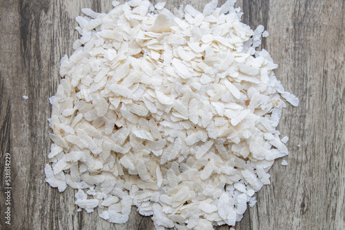 Flattened rice flakes on wooden texture, use to make healthy indian recipe poha