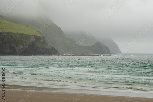 Stunning nature scenery and Keem beach, county Mayo, Ireland. Popular travel area with surfing and sightseeing. Irish landscape. Low clouds, rainy day. Stormy weather.