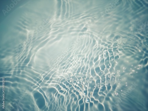 Defocus blurred transparent blue colored clear calm water surface texture with splashes and bubbles. Trendy abstract nature background. Water waves in sunlight with copy space. Blue watercolor shining