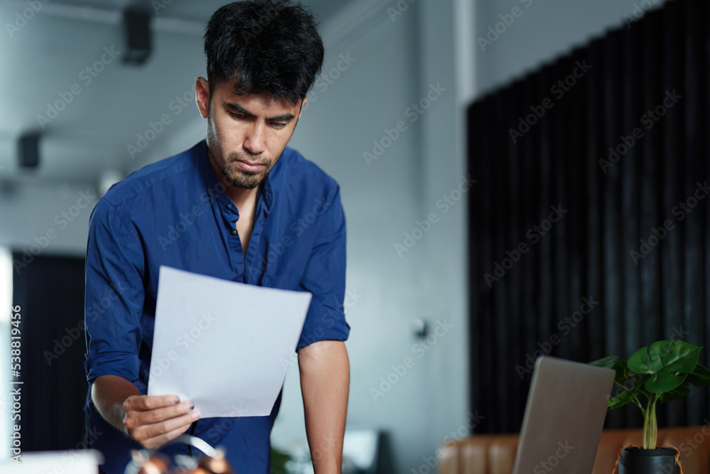 A portrait of a good-looking and discreet Asian man sitting at his desk with a thoughtful look on his computer A portrait of a good-looking and discreet Asian man sitting at his desk with a thoughtful look on his computer
