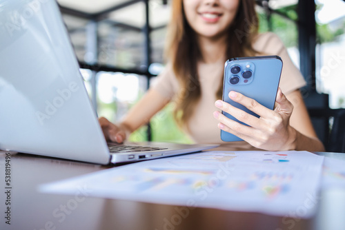 Close-up freelancer woman hands working on smartphone and laptop in a cafe. Working online technology and modern devices concept