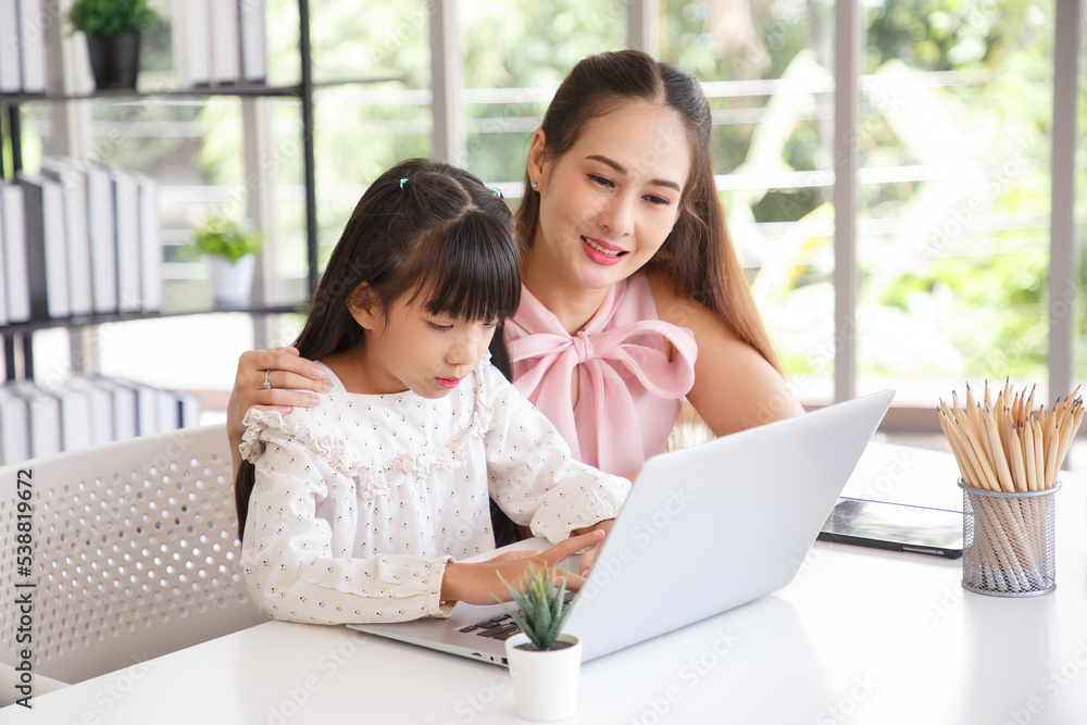 Children education and home school concept : Young asian mother pleased to see little daughters' study online. Excited smiling child girl enjoying online learning with pleasant mom at home. Children education and home school concept : Young asian mother pleased to see little daughters' study online. Excited smiling child girl enjoying online learning with pleasant mom at home.