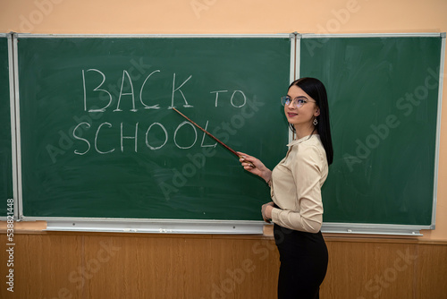 young pretty teacher standing near classboard photo