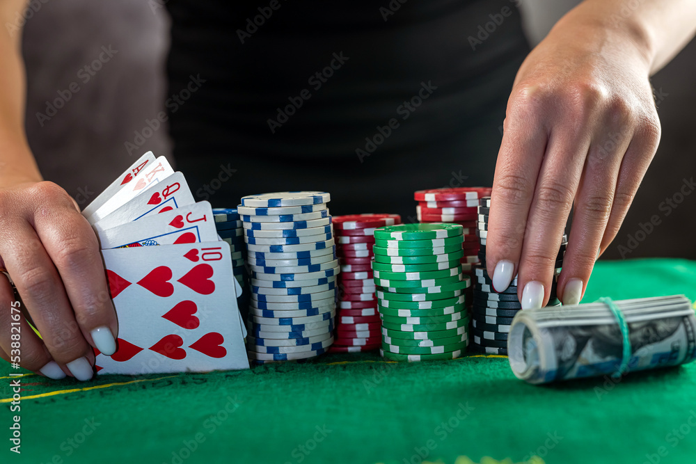Female hand taking poker chips from pile at round poker table. Female hand taking poker chips from pile at round poker table.