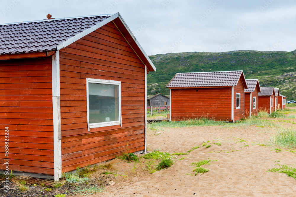 Red wooden houses on the sandy beach of the Barents Sea. Teriberka. Russia Red wooden houses on the sandy beach of the Barents Sea. Teriberka. Russia