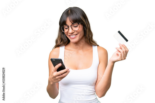 Young caucasian woman over isolated background buying with the mobile with a credit card