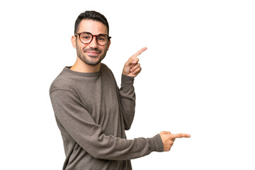 Young handsome caucasian man over isolated background pointing finger to the side and presenting a product