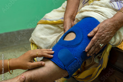 Close up of old lady wearing knee cap feeling pain. Concept of knee pain and therapy. Selective focus