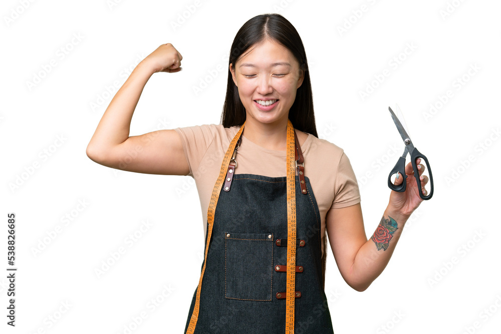 Young Asian seamstress woman over isolated background doing strong gesture Young Asian seamstress woman over isolated background doing strong gesture