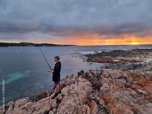 Boy fishing at sunset, Gracetown, Western Australia 