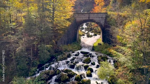Indian summer in austria  - a little river running down a hill surounding many mossy rocks, passing a litle bride photo
