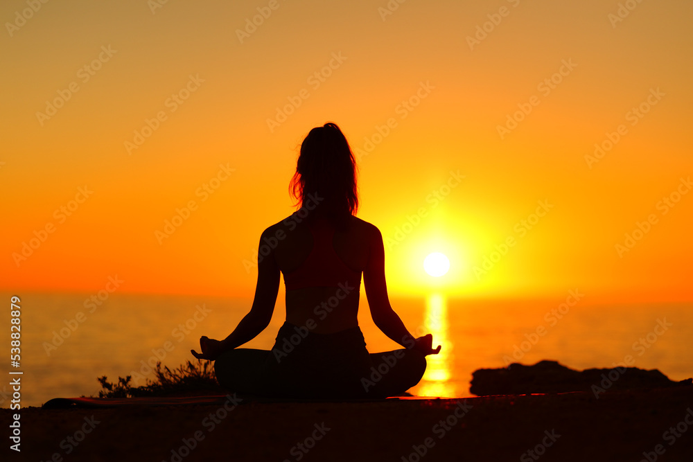 Silhouette of a woman doing yoga with sunset sun Silhouette of a woman doing yoga with sunset sun
