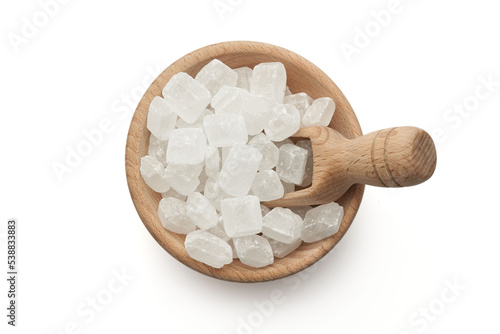 Cukier biały lodowy w dużych kostkach w drewnianej miseczce z łopatką na białym tle