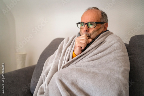 Man wrapped in blanket shivering at home