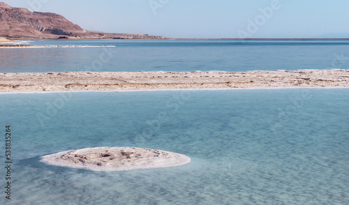 industrial salt evaporation ponds in the southern section of the Dead Sea Yam Hamelah in Israel showing mineral formations with a hazy blue sky background photo
