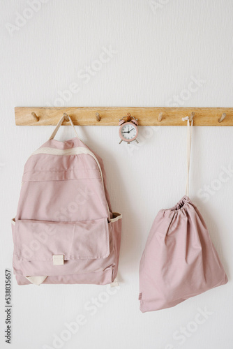 Pink color backpacks and alarm clock hanging on hook