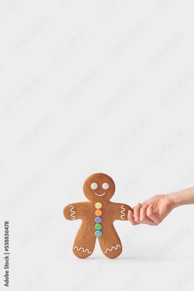 Hand of woman holding freshly backed gingerbread cookie against white background
