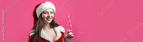 Beautiful young woman in Santa Claus costume against the red background.
