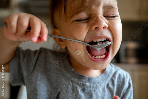 Baby boy eating porridge with spoon photo